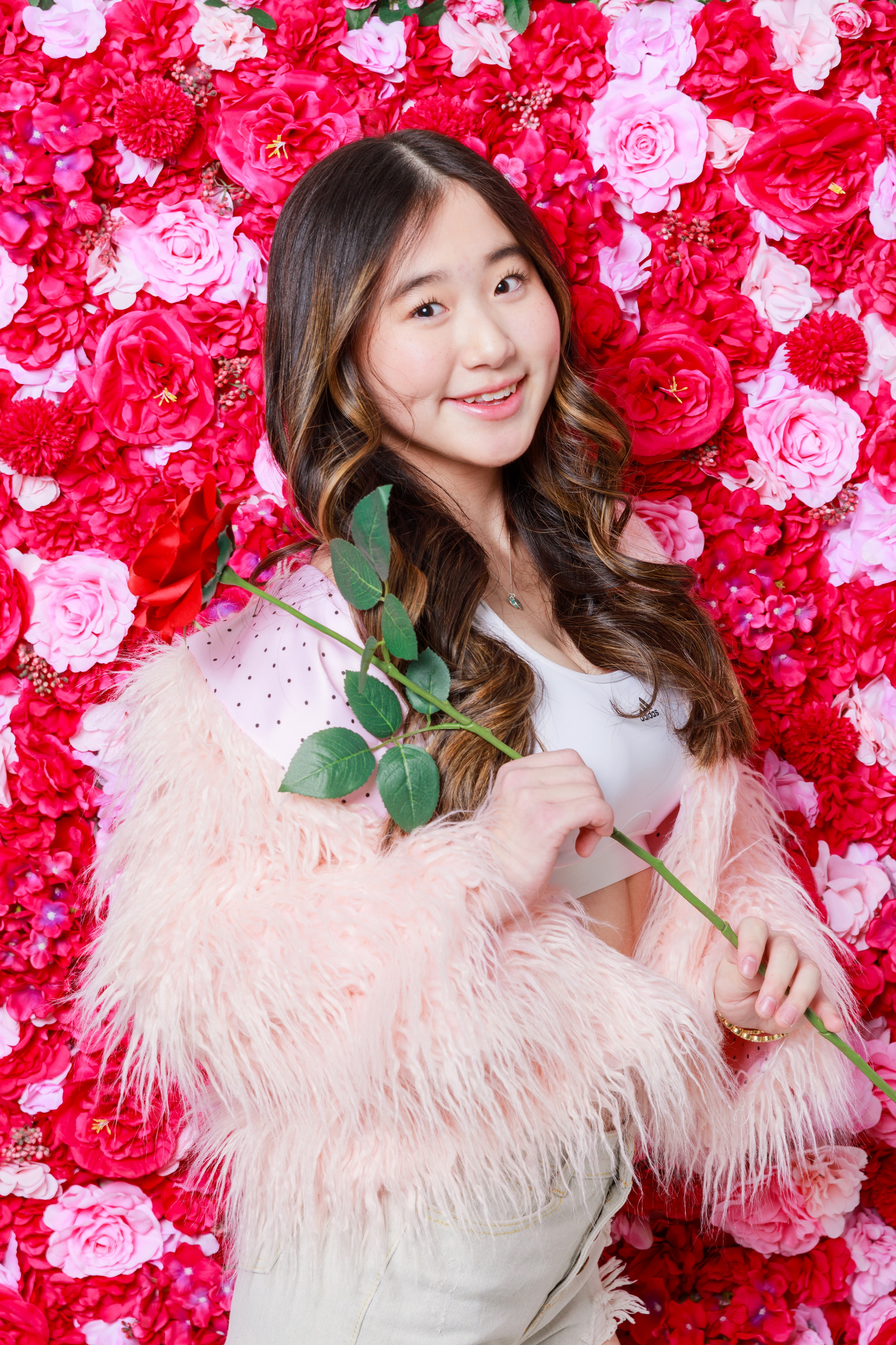 Sarah smiling in front of pink and red flowers